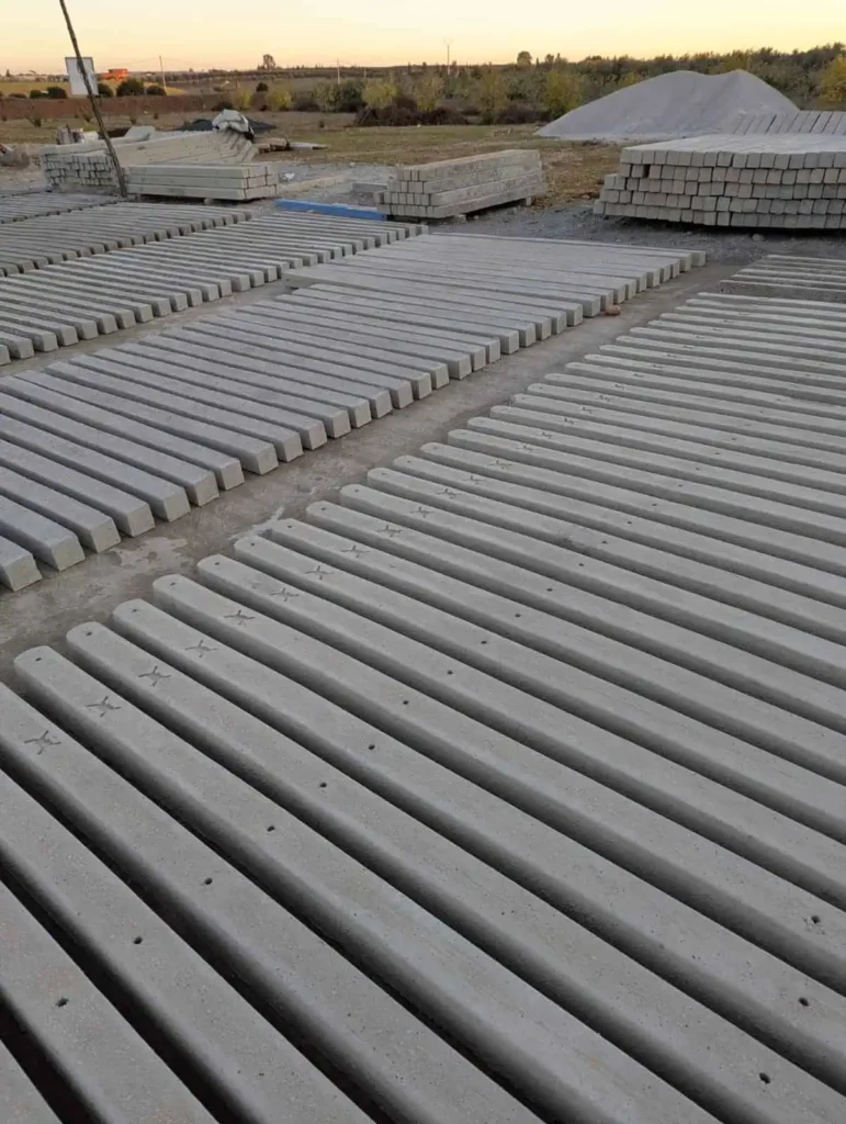 Un grand stock de poteaux en béton armé perforés prêts pour l'installation de clôtures de protection agricoles.