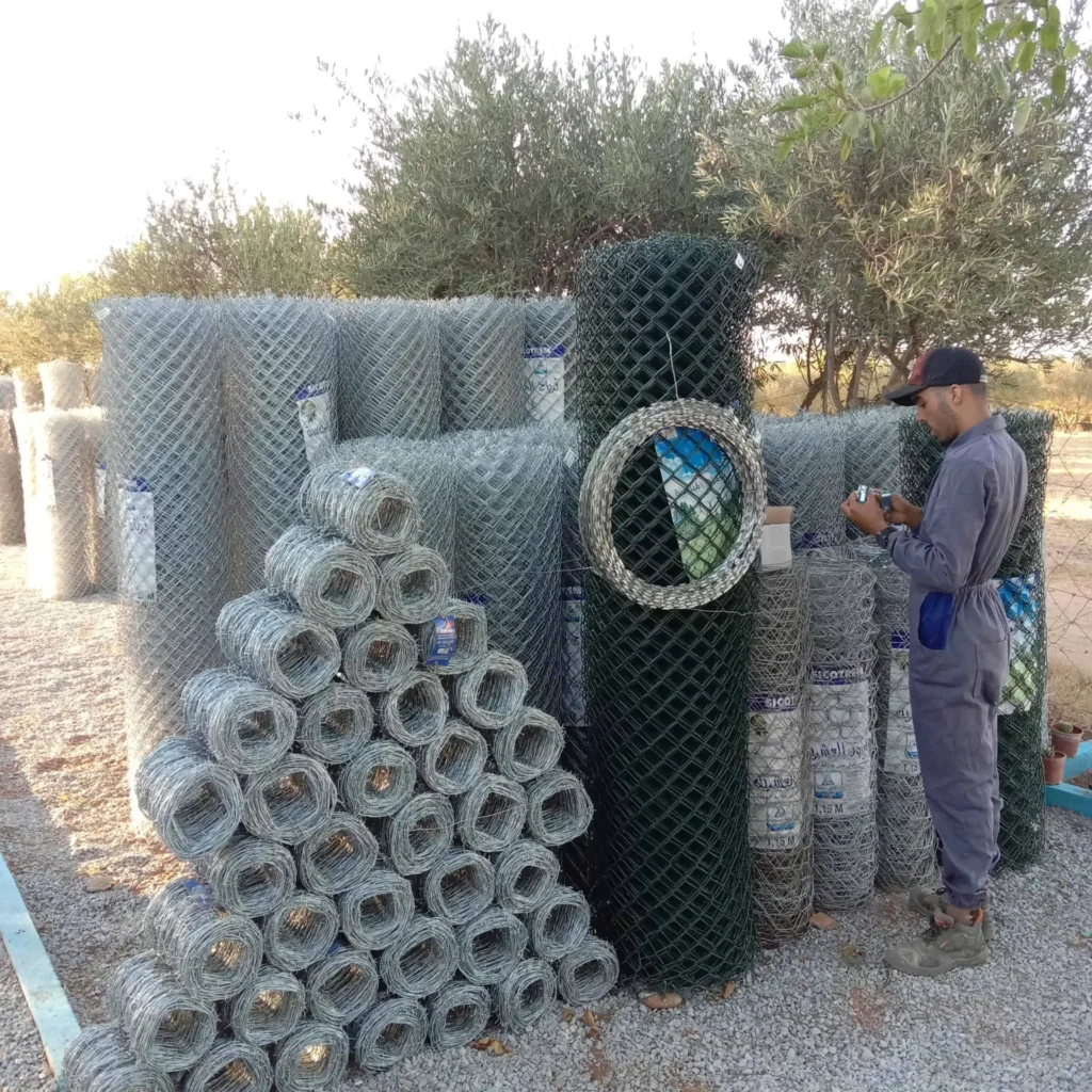Rouleaux de grillage simple torsion vert et galvanisé avec fil de fer barbelé concertina pour clôture agricole.